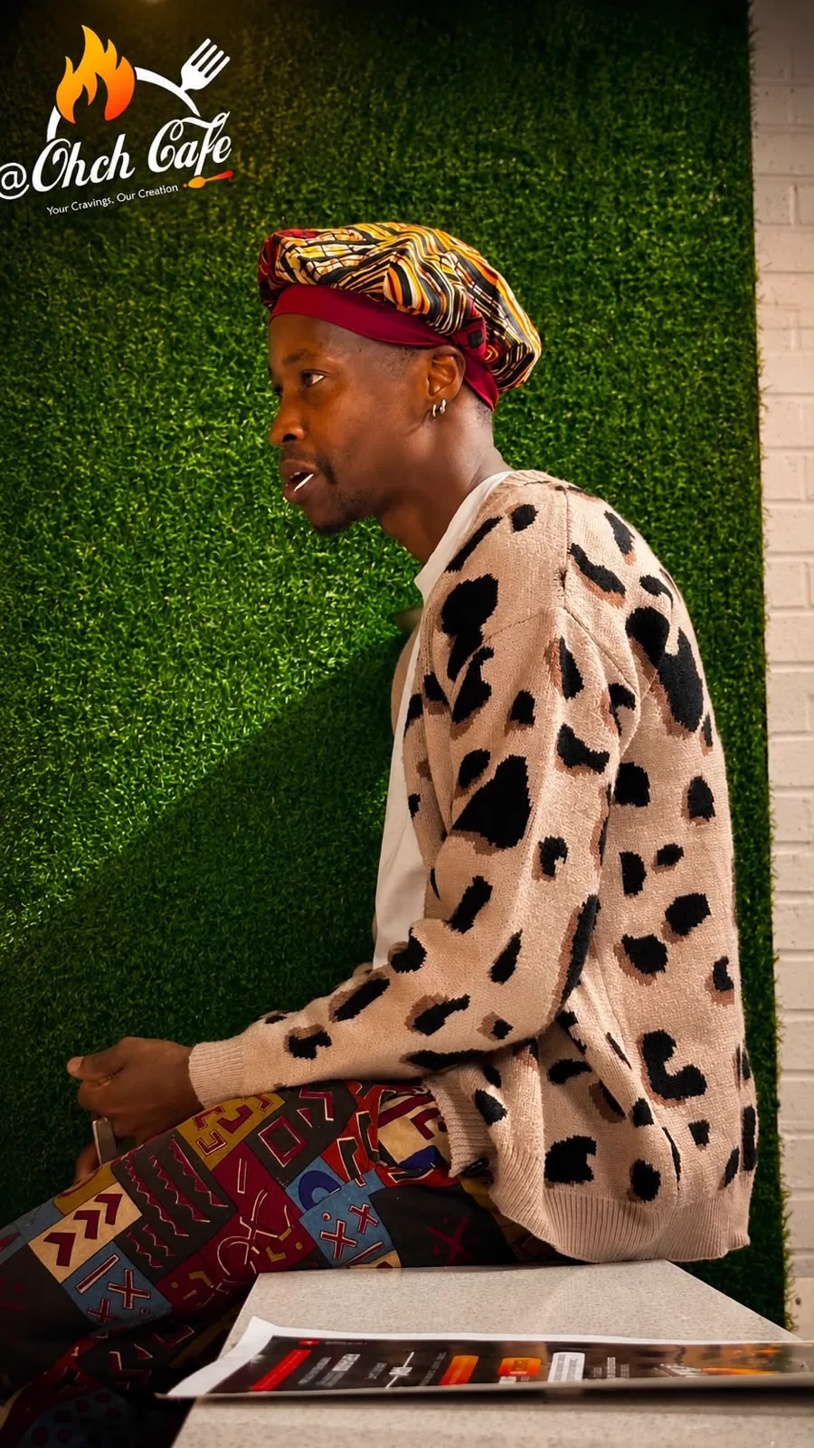 A guest in African print seated at OHCH.CAFE